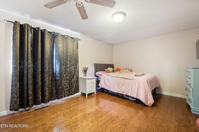 bedroom with ceiling fan, hardwood / wood-style floors, and a textured ceiling