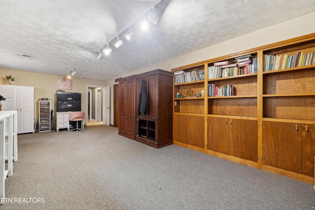 unfurnished living room with light carpet, track lighting, and a textured ceiling