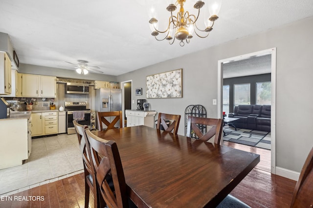 dining room featuring sink, ceiling fan with notable chandelier, light hardwood / wood-style floors, and a textured ceiling