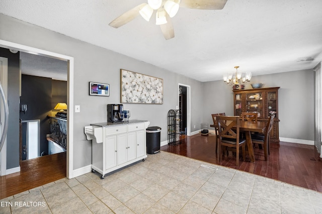 tiled dining area featuring ceiling fan with notable chandelier