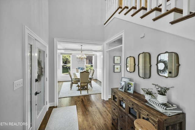 foyer entrance with dark wood-style floors, a chandelier, and a towering ceiling