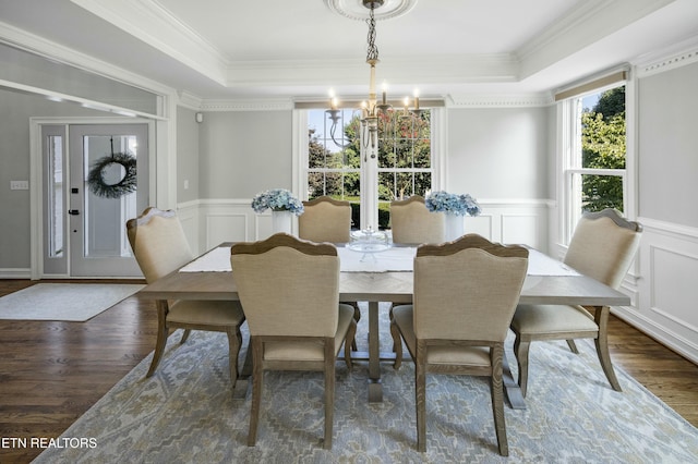 dining area featuring a raised ceiling, a wainscoted wall, wood finished floors, crown molding, and a notable chandelier