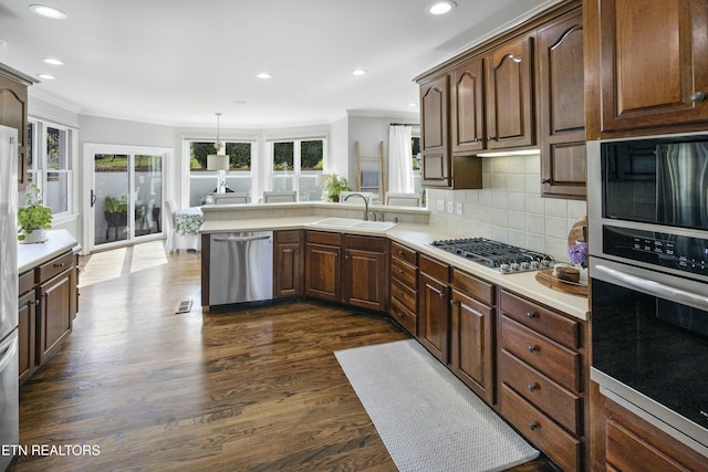 kitchen featuring crown molding, tasteful backsplash, light countertops, appliances with stainless steel finishes, and a sink