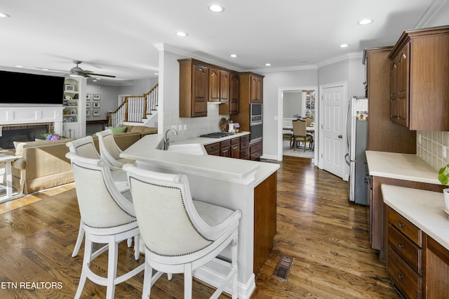 kitchen with dark wood-type flooring, a sink, a kitchen breakfast bar, light countertops, and freestanding refrigerator