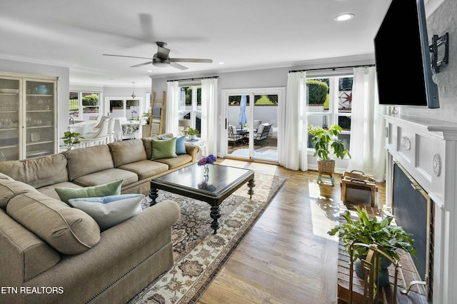 living room with a fireplace, recessed lighting, ornamental molding, ceiling fan, and wood finished floors