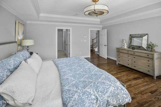 bedroom with ornamental molding, a raised ceiling, and wood finished floors