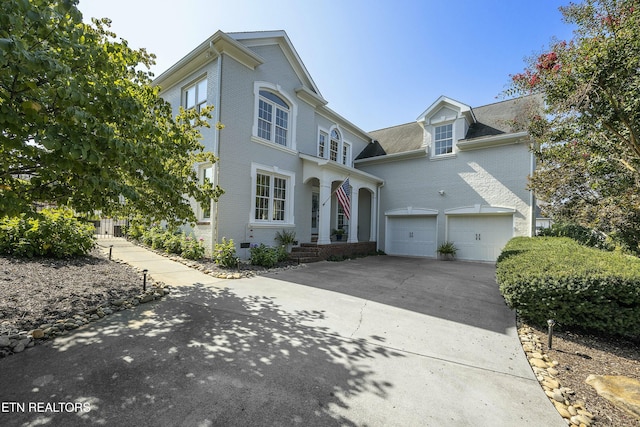 traditional-style house with an attached garage, concrete driveway, and brick siding