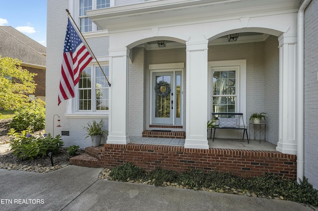 property entrance featuring covered porch and brick siding