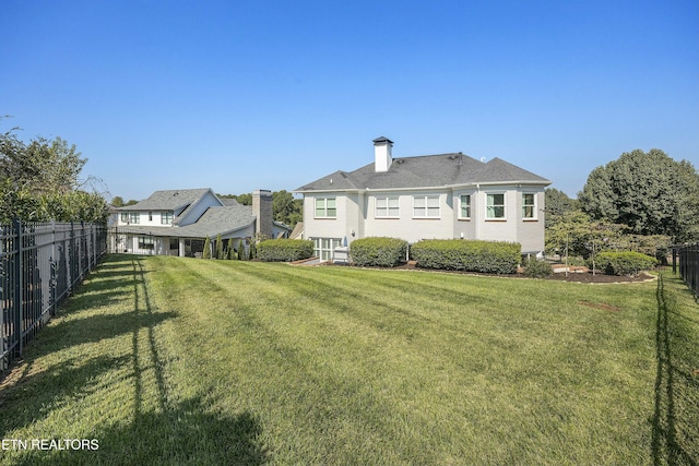 rear view of property with a lawn and fence