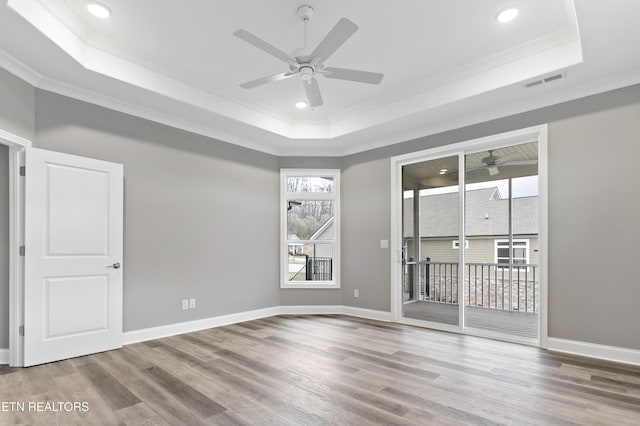 empty room with hardwood / wood-style flooring, a tray ceiling, and crown molding