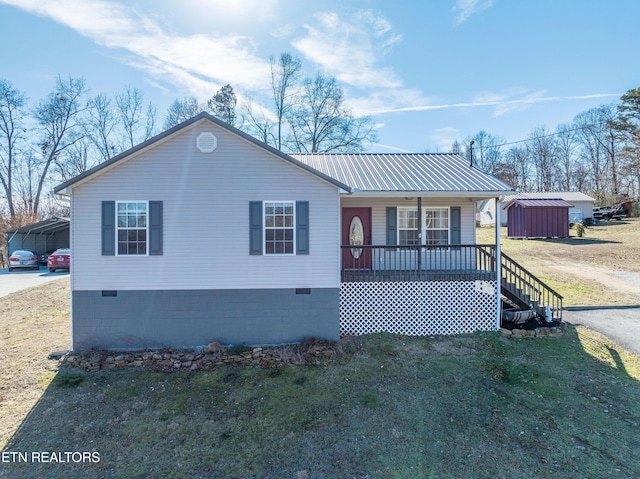 view of front of property featuring a shed, a front yard, a carport, and covered porch