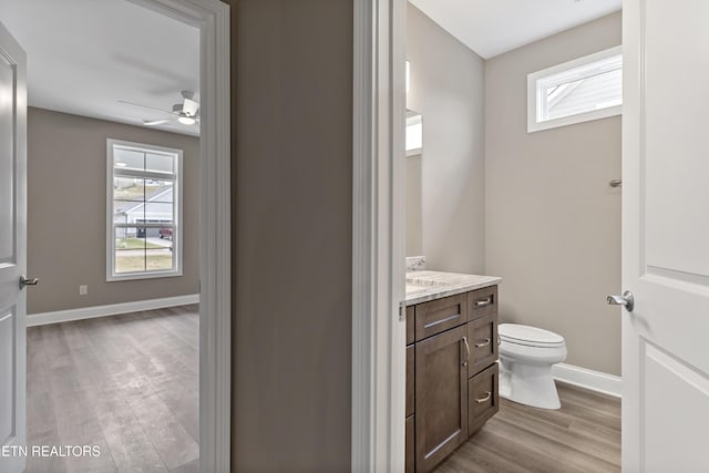 bathroom with hardwood / wood-style flooring, a healthy amount of sunlight, toilet, and vanity