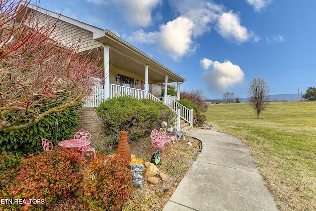 view of side of home featuring a lawn and a porch