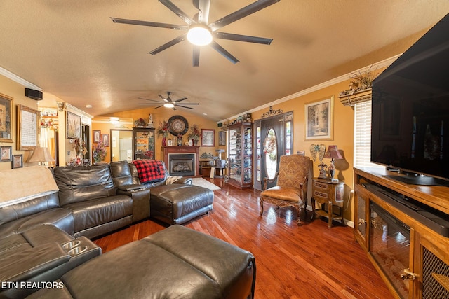 living room with lofted ceiling, a textured ceiling, ornamental molding, hardwood / wood-style flooring, and ceiling fan