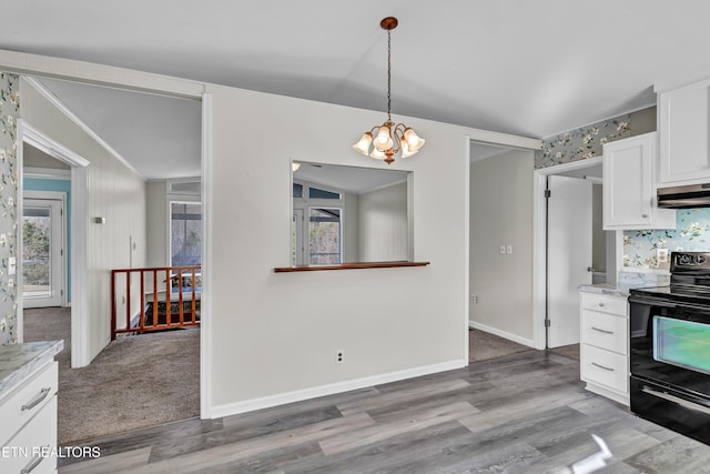 kitchen featuring light wood-style flooring, black range with electric stovetop, under cabinet range hood, white cabinetry, and pendant lighting