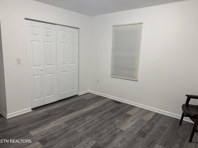 unfurnished bedroom featuring dark wood-type flooring and a closet