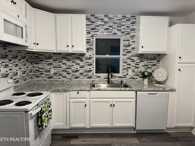 kitchen featuring tasteful backsplash, sink, white cabinets, light stone countertops, and white appliances