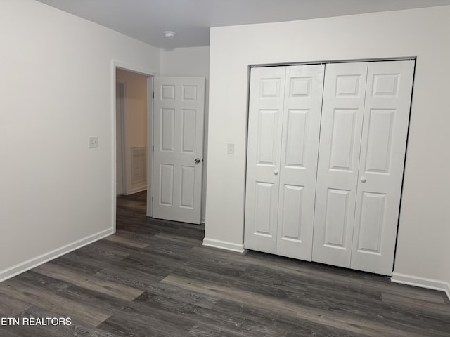 unfurnished bedroom featuring dark hardwood / wood-style flooring and a closet