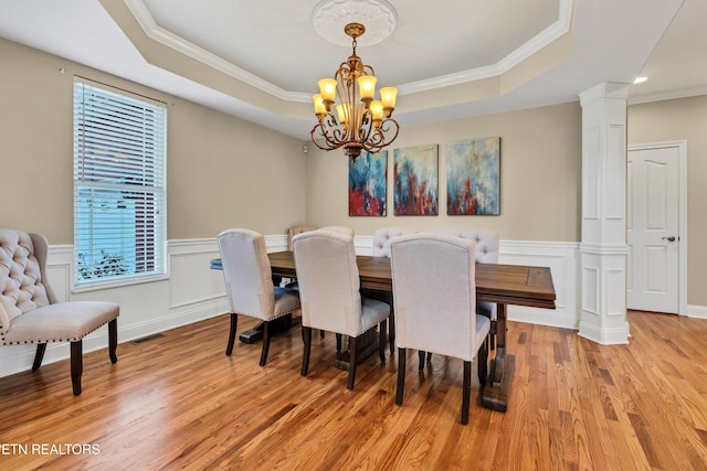 dining area with an inviting chandelier, a tray ceiling, ornamental molding, and light hardwood / wood-style floors