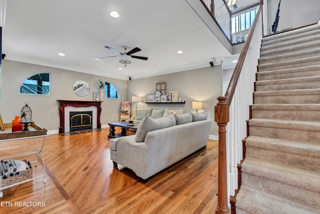 living room with crown molding, ceiling fan, a fireplace, and hardwood / wood-style floors