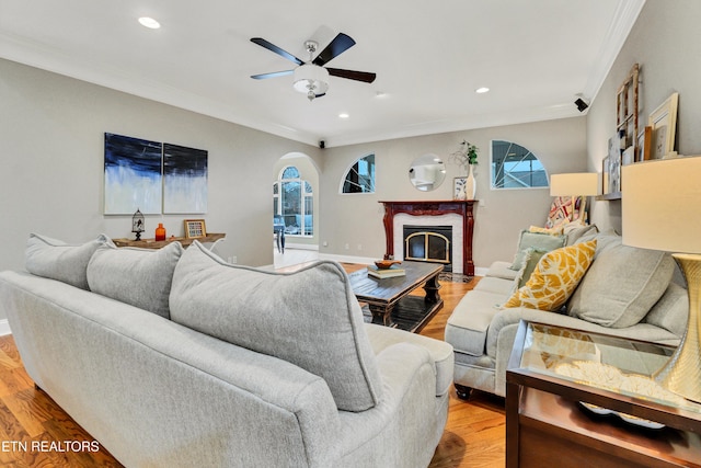 living room featuring crown molding, light hardwood / wood-style flooring, and ceiling fan