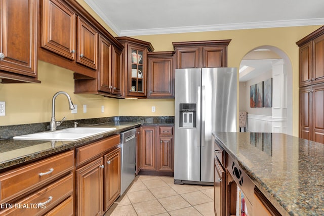 kitchen with ornamental molding, appliances with stainless steel finishes, sink, and dark stone counters