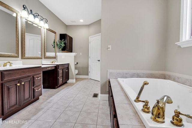 bathroom featuring toilet, vanity, tiled bath, and tile patterned flooring