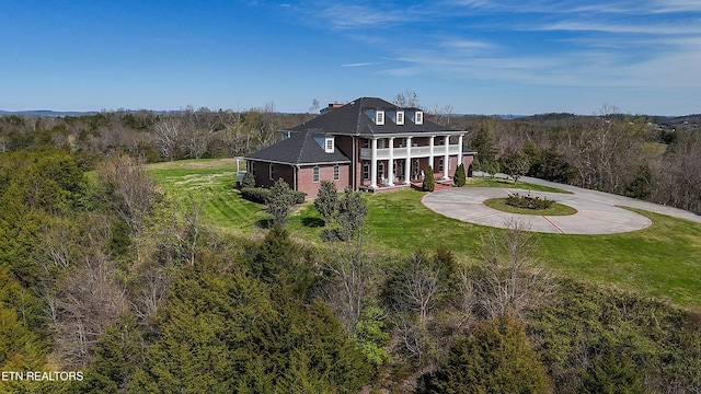 back of property featuring covered porch and a lawn