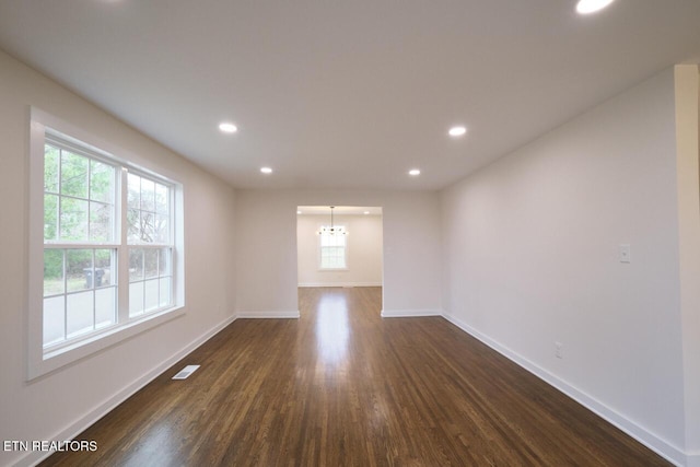 empty room featuring an inviting chandelier and dark wood-type flooring