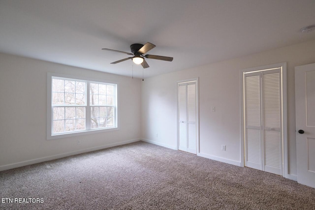 unfurnished bedroom featuring multiple closets, carpet, and ceiling fan