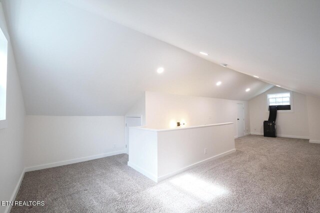 bonus room featuring vaulted ceiling and light colored carpet