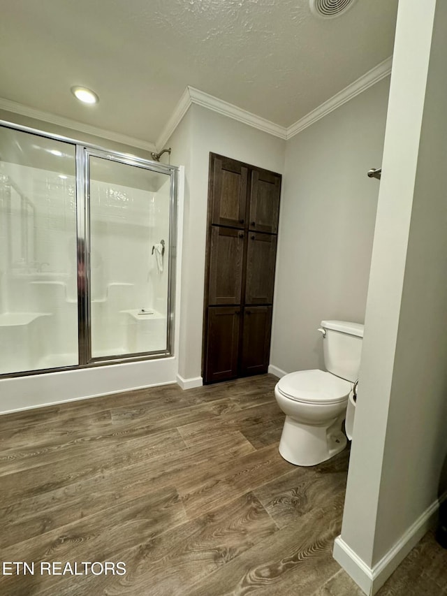 bathroom featuring a shower stall, crown molding, baseboards, and wood finished floors