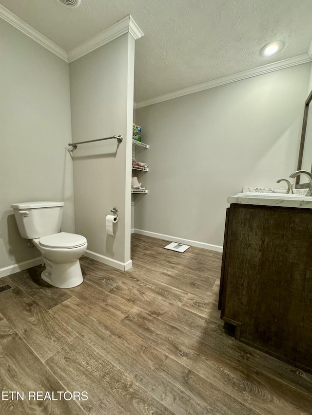 half bathroom featuring crown molding, wood finished floors, and vanity