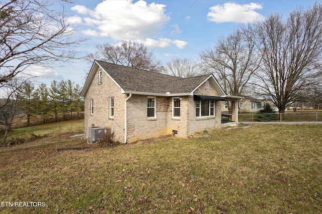 view of property exterior featuring roof with shingles, fence, cooling unit, a yard, and brick siding