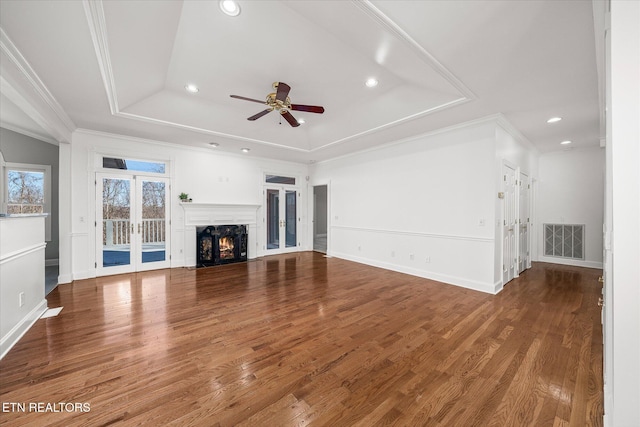 unfurnished living room featuring crown molding, hardwood / wood-style flooring, ceiling fan, french doors, and a raised ceiling