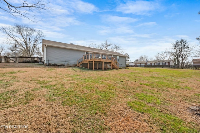 rear view of house featuring a wooden deck and a yard