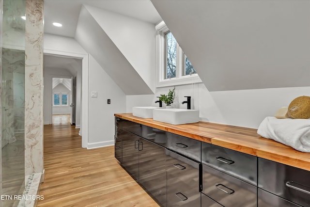 bonus room featuring vaulted ceiling, sink, and light wood-type flooring