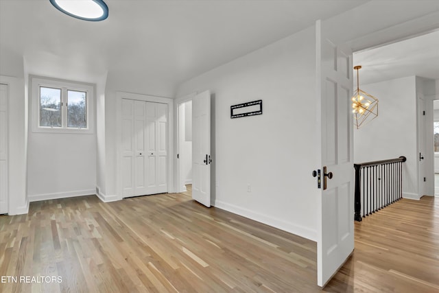 empty room with a notable chandelier and light wood-type flooring