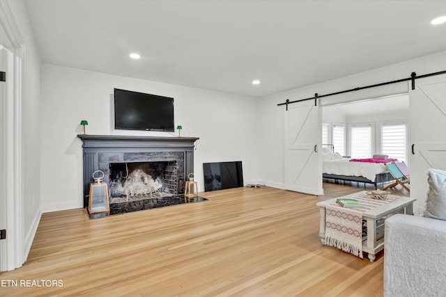 living room with a barn door, hardwood / wood-style floors, and a tile fireplace