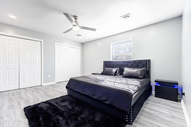 bedroom with multiple closets, ceiling fan, and light hardwood / wood-style flooring