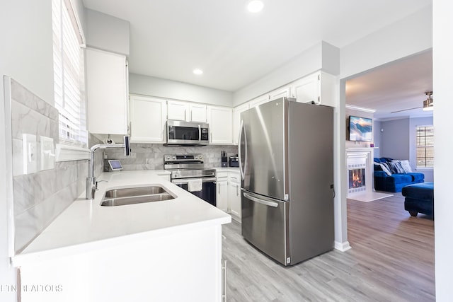 kitchen featuring stainless steel appliances, sink, white cabinets, and kitchen peninsula