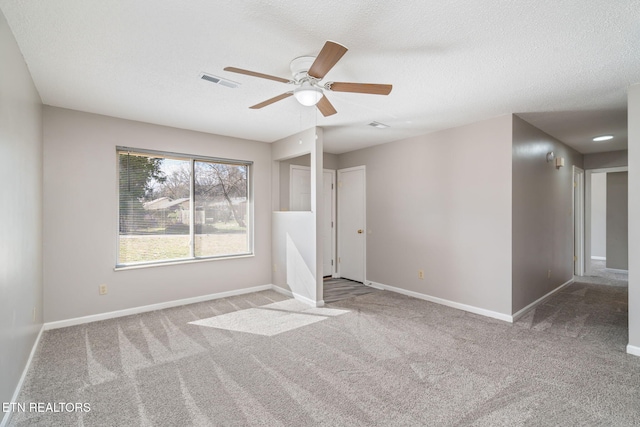 unfurnished room featuring ceiling fan, light colored carpet, and a textured ceiling