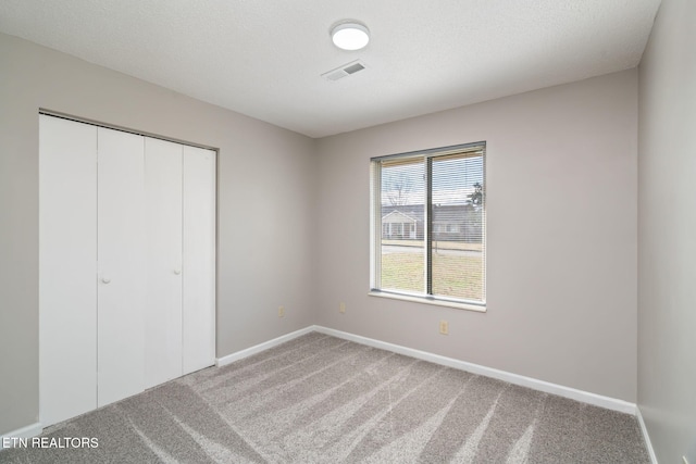 unfurnished bedroom featuring carpet floors, a textured ceiling, and a closet