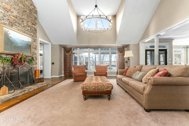 living room featuring ornate columns, high vaulted ceiling, a notable chandelier, a fireplace, and hardwood / wood-style floors