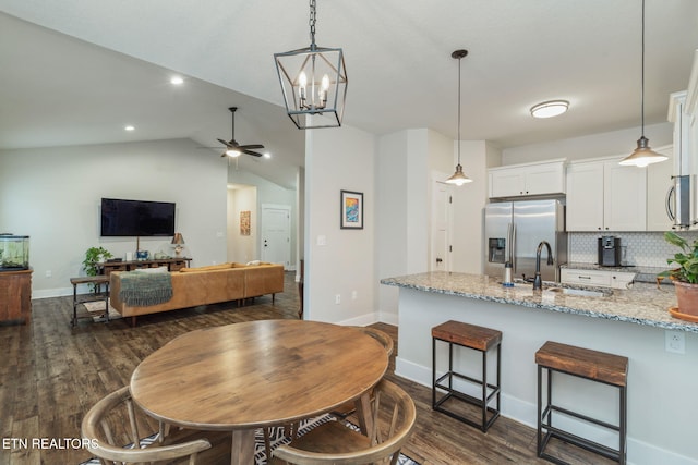 kitchen with appliances with stainless steel finishes, sink, white cabinets, hanging light fixtures, and light stone countertops