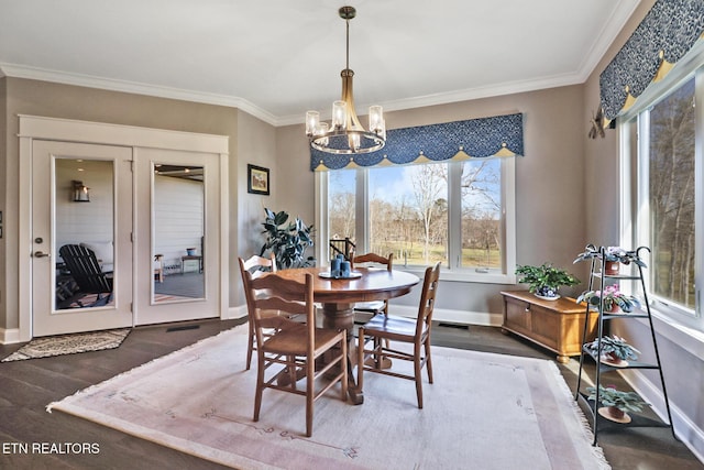 dining area featuring dark wood-type flooring, ornamental molding, and a chandelier