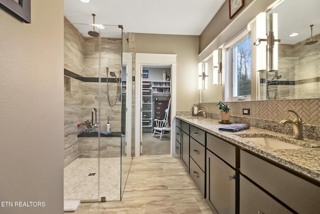 bathroom featuring vanity, backsplash, and walk in shower