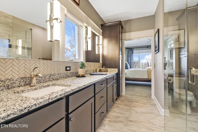 bathroom featuring tasteful backsplash, vanity, walk in shower, and toilet