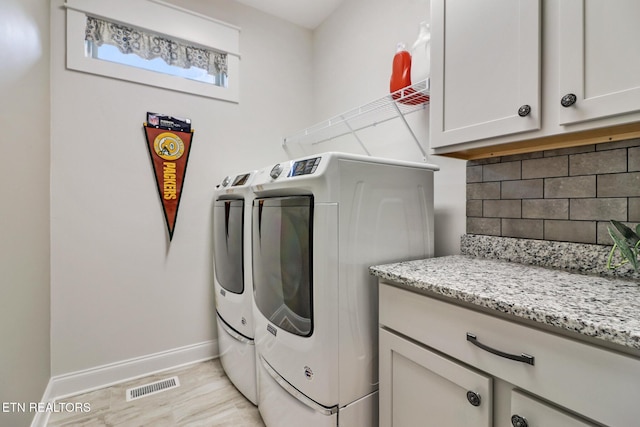 laundry room with cabinets, independent washer and dryer, and light hardwood / wood-style flooring