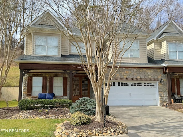 view of front of house with an attached garage, stone siding, concrete driveway, and roof with shingles